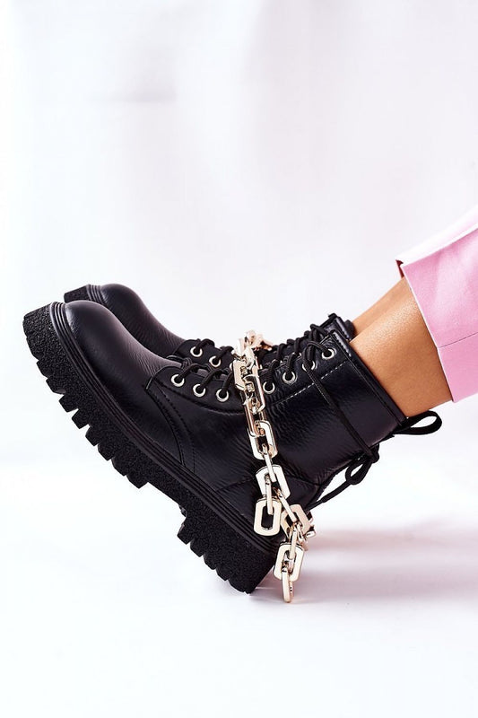 Close-up of luxury women's eco-leather black boots adorned with a gold chain, showcasing contemporary style and elegance.