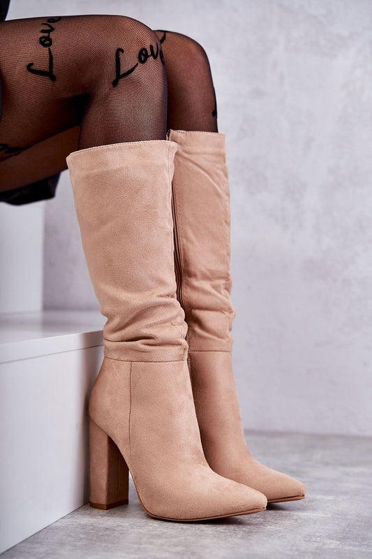 Elegant luxury pointed toe Cossack heel boots in soft beige suede, featuring a zippered front and warm insulation, styled elegantly with fishnet tights. Perfect for versatile fashion, ideal for both dresses and skirts.