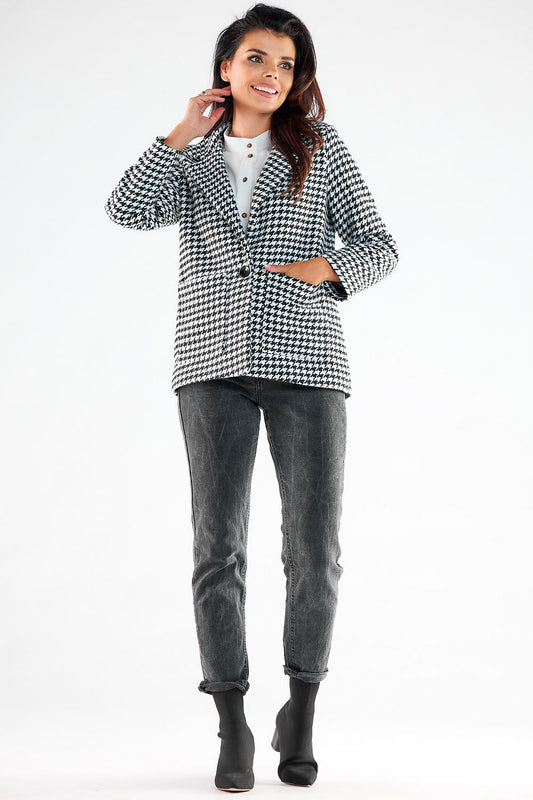 Graceful model showcasing a fashionable Awama houndstooth jacket with elegant button details and square pockets, styled effortlessly with dark jeans and ankle boots, embodying modern luxury.