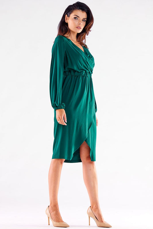 Sophisticated side profile of a model wearing a green long-sleeved Awama cocktail dress with a V neckline and a graceful slit, exuding luxury and elegance.