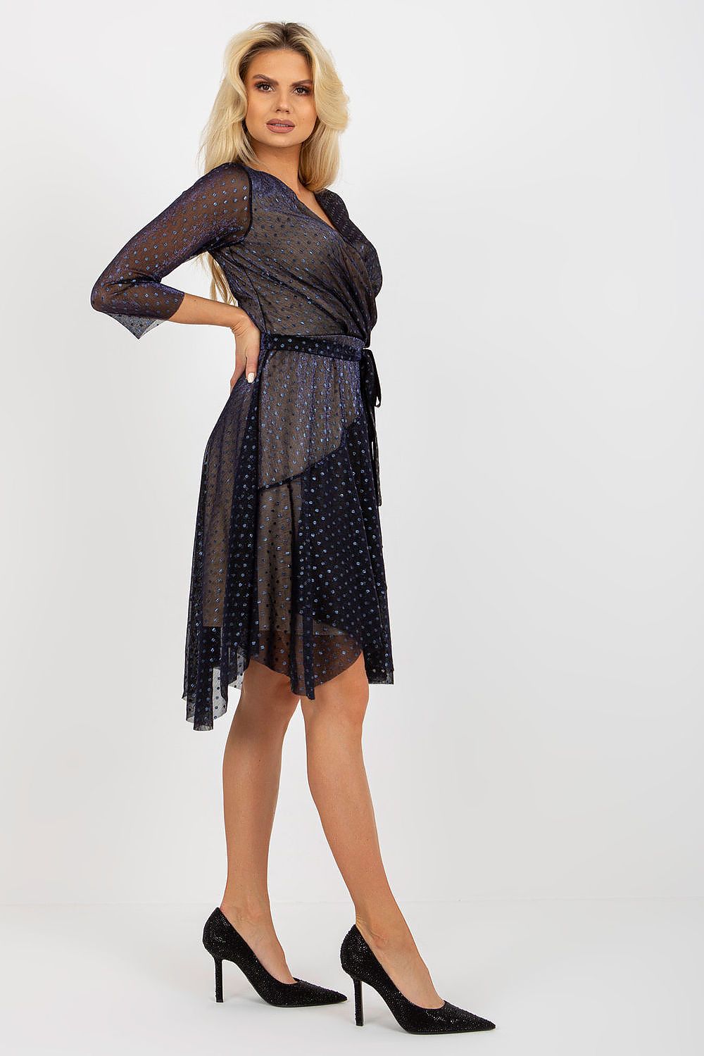 Sophisticated woman in a navy cocktail dress with an envelope front and 3/4 sleeves, emphasizing the stylish waist tie and a graceful silhouette.