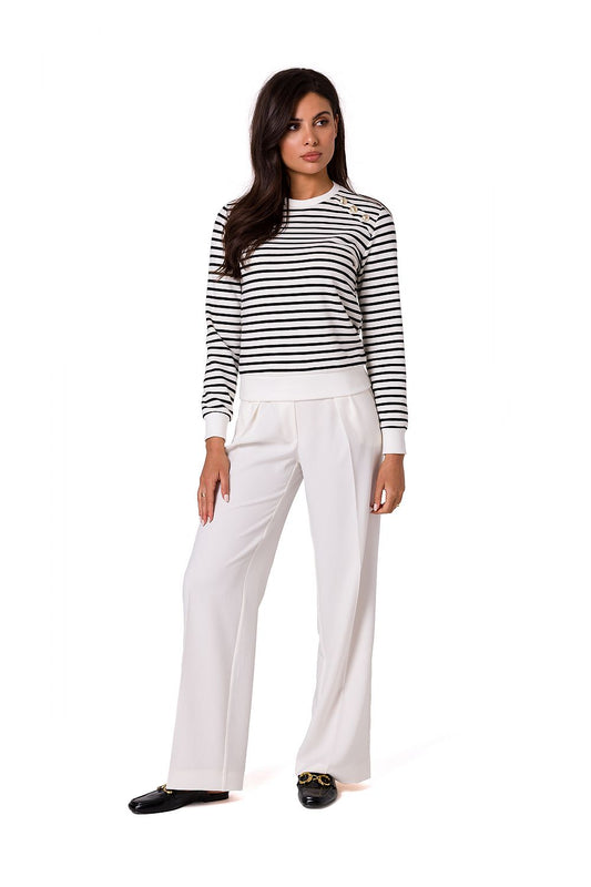 Sophisticated model in a navy striped cotton knit sweatshirt with decorative gold buttons by BeWear, paired with fashionable white wide-legged trousers for a refined look.