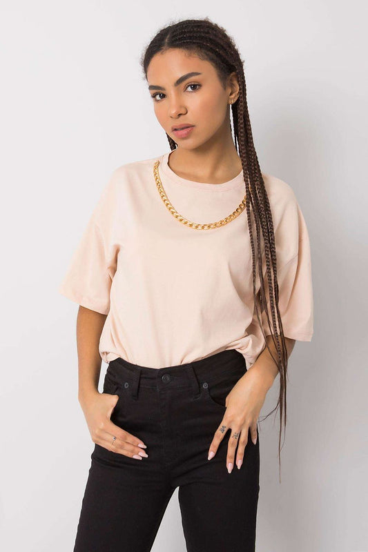 Elegant women's loose fit t-shirt by Rue Paris, showcasing a stylish decorative chain, paired with black pants and a confident pose, set against a minimalist backdrop.