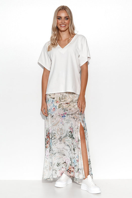 Stylish outfit featuring a woman in a white cotton blouse by Makadamia, paired with a floral maxi skirt, portraying a versatile and elegant spring look.