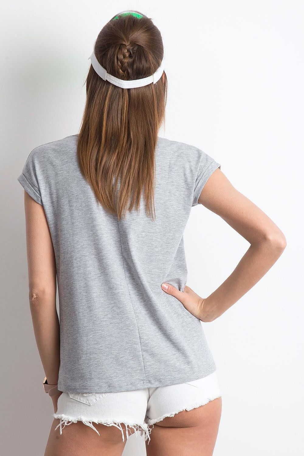 Sophisticated back view of a woman wearing a grey V-neck t-shirt by BFG, accentuating minimalist fashion with casual shorts and a trendy visor.