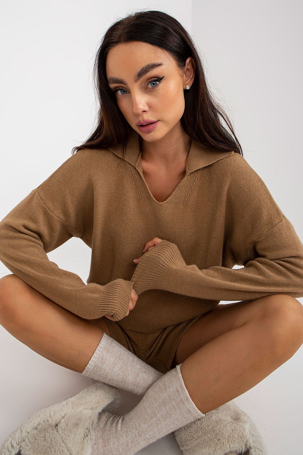 Elegant model in a luxury casual ensemble by EM, showcasing a soft brown sweater and matching shorts, paired with chic ribbed socks and plush slippers for a sophisticated yet comfortable look.