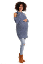 A model showcasing stylish maternity wear in a luxurious blue half-zip sweater, designed for comfort and warmth during pregnancy, paired with distressed jeans and chic ankle boots.