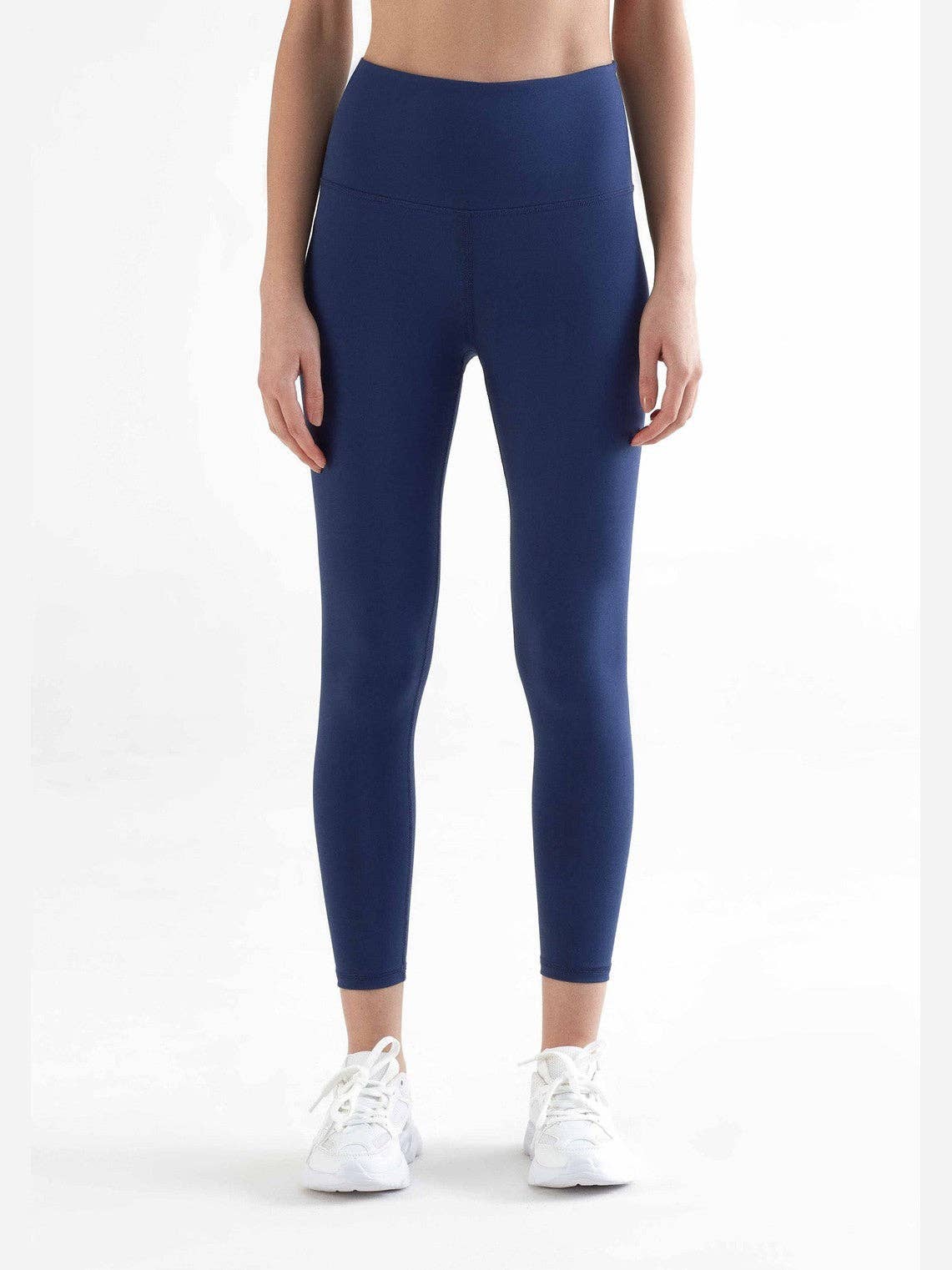 Woman wearing high-rise organic 7/8 stretch leggings in modern cut, showcasing a stylish look above the ankle.