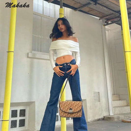 Chic Off-Shoulder Crop Sleeve Tee with Slim Fit & Vintage Harajuku Style, worn by a model posing confidently in flared jeans, emphasising the tee's cropped silhouette and stylish appeal in a vibrant urban setting.