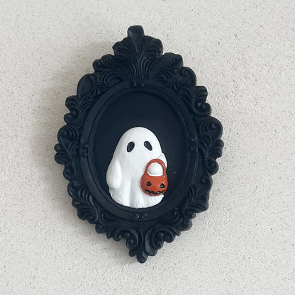 Sophisticated Halloween Resin Ornament - Trick or Treat Ghost Wall Decoration. Captivating ghost figure holding a pumpkin sits within an ornate black frame, perfect for festive interior design.