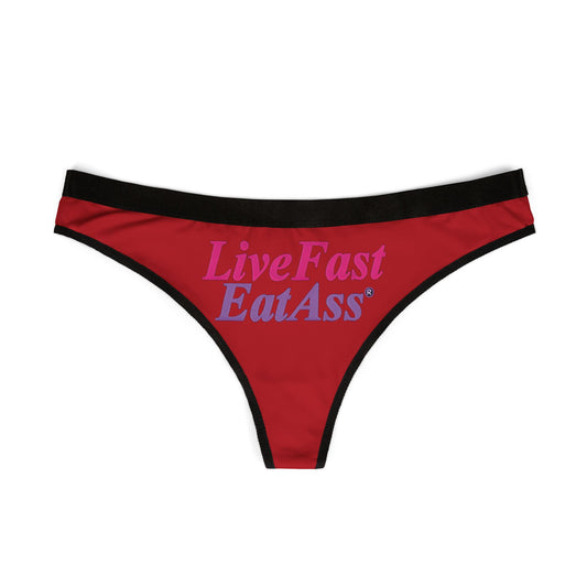 Luxurious red thong panties featuring the bold slogan 'Live Fast Eat Ass' in stylish typography, bordered with a sophisticated black waistband.