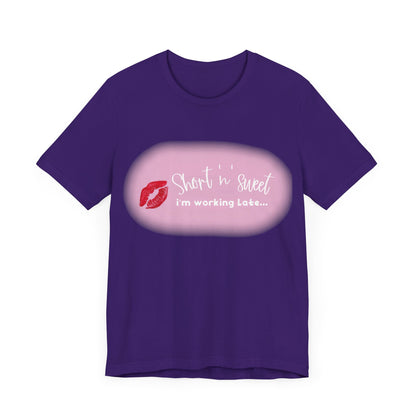 Sabrina Carpenter Inspired Unisex Short Sleeve Tee in rich purple featuring a fashionable lipstick print reading 'Short 'n Sweet, I'm Working Late...'