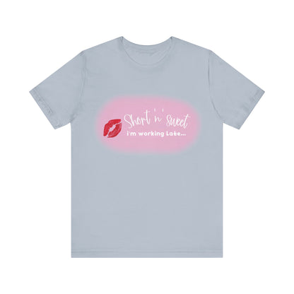 Sabrina Carpenter Inspired Unisex Short Sleeve Tee in gentle grey, adorned with a striking lipstick print and the text 'Short 'n' sweet, I'm working Late...' combining comfort and elegance.