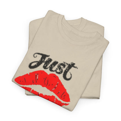 Stacked unisex graphic tees showcasing a striking design of bold red lips and the whimsical text 'Just Kiss Me!' in a chic beige colour.