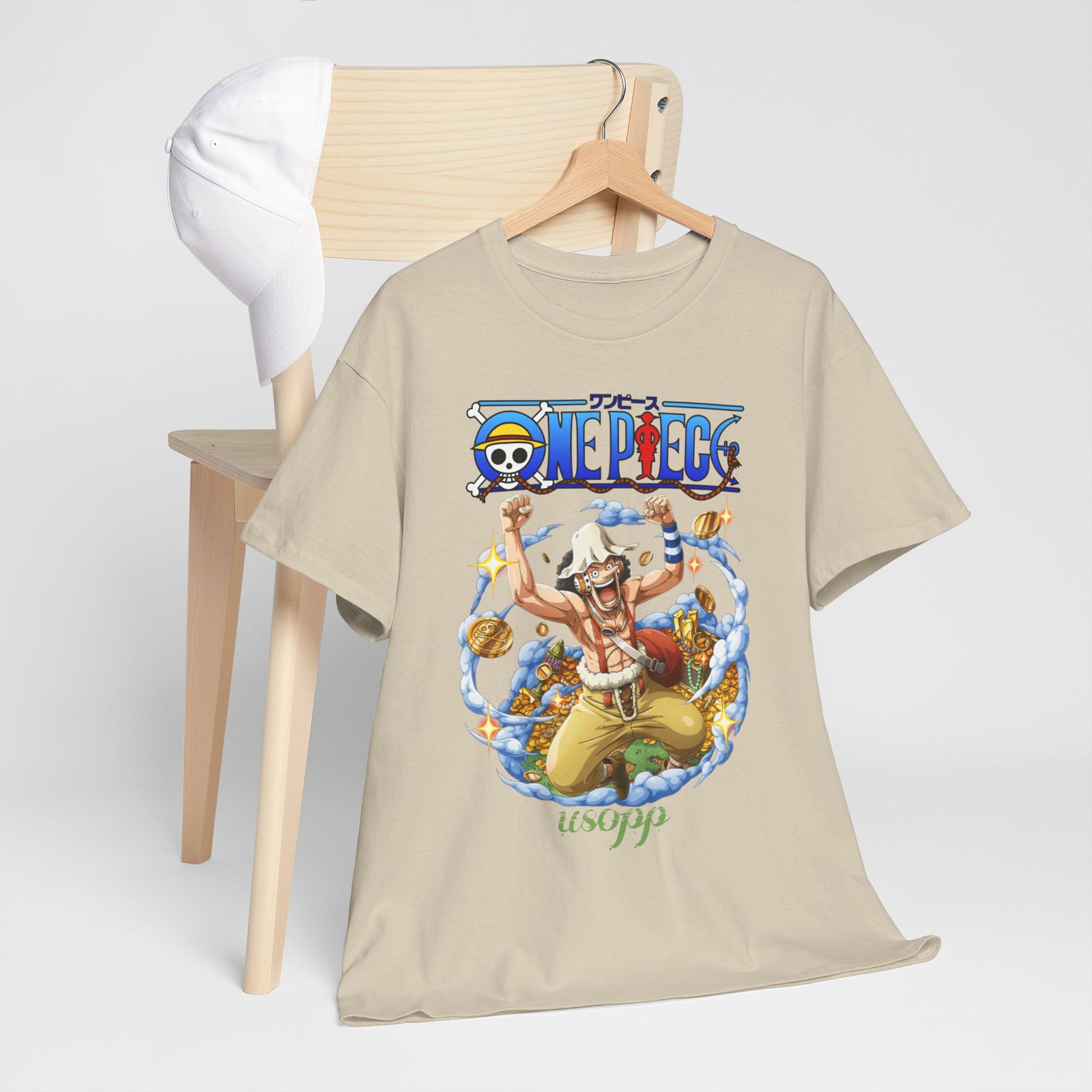Dynamic Usopp men's t-shirt in beige featuring vibrant artwork and a One Piece theme, elegantly displayed on a minimalist wooden chair with a matching cap.