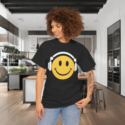 Enchanted Harmony Graphic T-Shirt worn by a model in a contemporary kitchen, displaying a chic black shirt featuring a yellow smiley face and stylish white headphones, perfect for urban fashion.