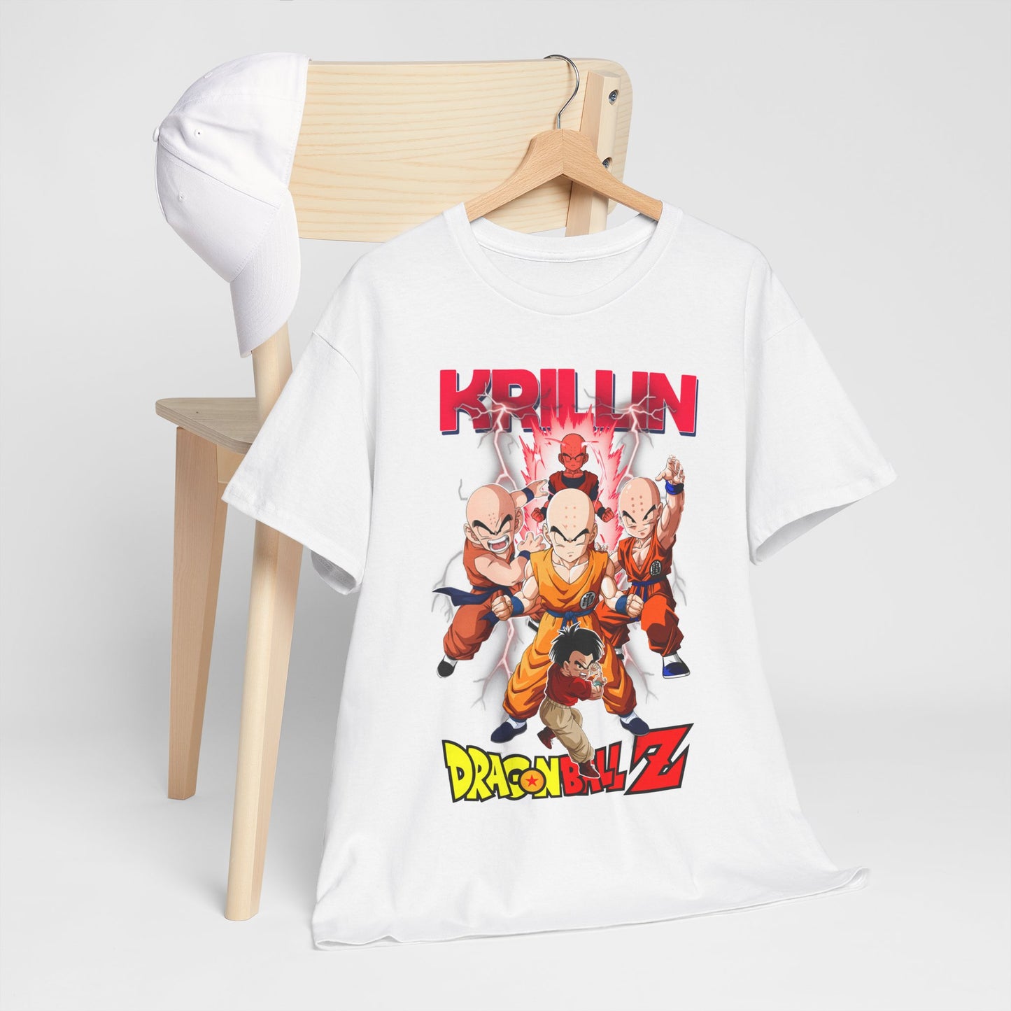 Stylish white Dragon Ball Z T-shirt showcasing Krillin and fellow Z warriors, artistically draped over a wooden chair with a matching cap.