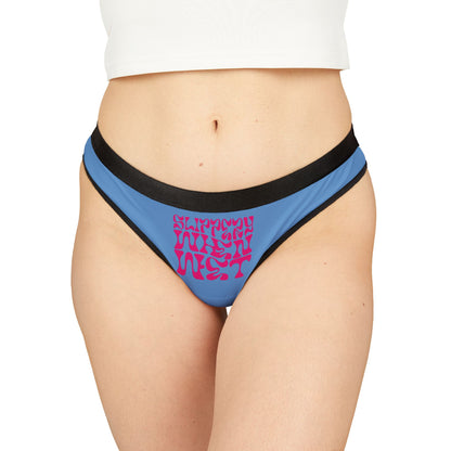 Chic model wearing exquisite blue thong panties adorned with 'SLIPPERY WHEN WET' text, embodying a playful yet sophisticated look for the modern femme fatale.