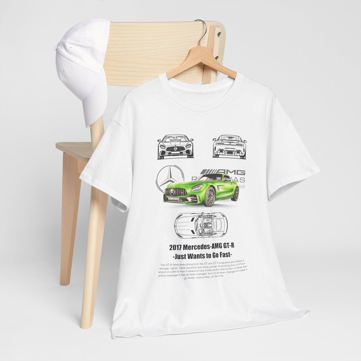Chic white T-shirt styled on a wooden chair alongside a white cap, featuring a detailed graphic representation of the Mercedes-AMG GT-R in vibrant green.