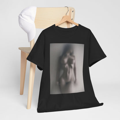 Luxurious black graphic t-shirt featuring a captivating misty design of an abstract human figure, elegantly displayed on a rustic wooden chair with a white cap in the background.