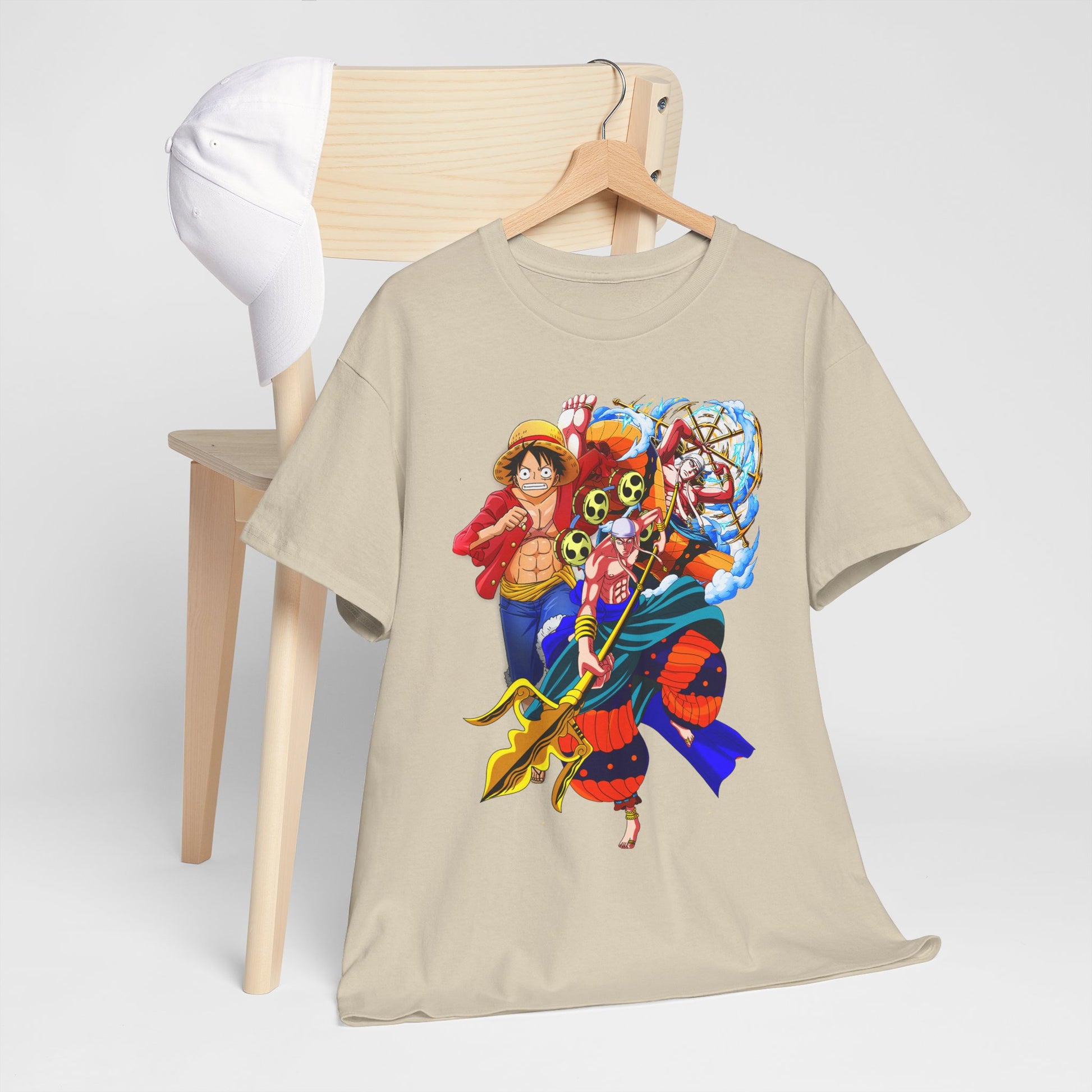 Stylish beige anime-inspired t-shirt displayed on a wooden chair with a fashionable cap, highlighting bold character illustrations.
