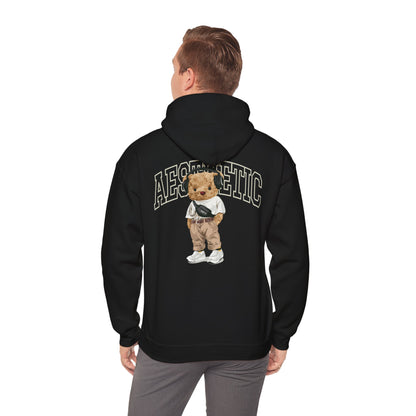 Elegant man wearing a black hoodie with a cartoon teddy bear illustration on the back, demonstrating a trendy aesthetic.