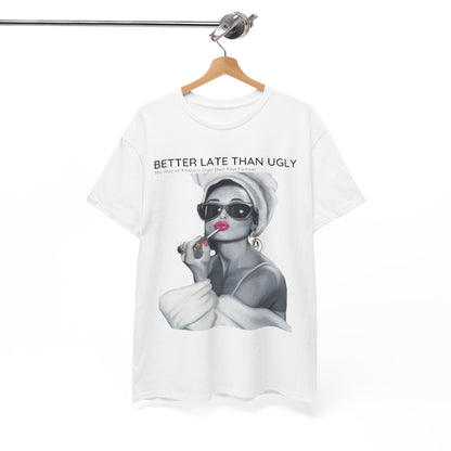 Stylish white t-shirt hanging on a wooden hanger, showcasing the bold phrase 'Better Late Than Ugly' alongside a chic illustration of a woman exuding sophistication, perfect for a timeless wardrobe.