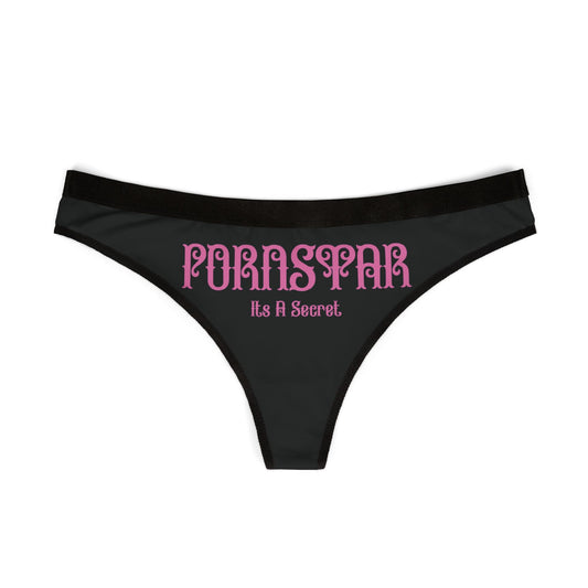 Elegant women's thong panties featuring the bold slogan 'PORNSTAR: It's a Secret' in stylised pink typography on a classic black background.