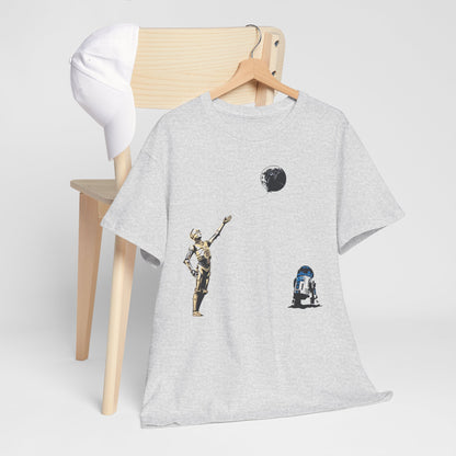 Stylish Star Wars T-Shirt depicting C-3PO and R2-D2 with a whimsical Death Star balloon, artfully arranged with a chic white cap on a wooden chair.