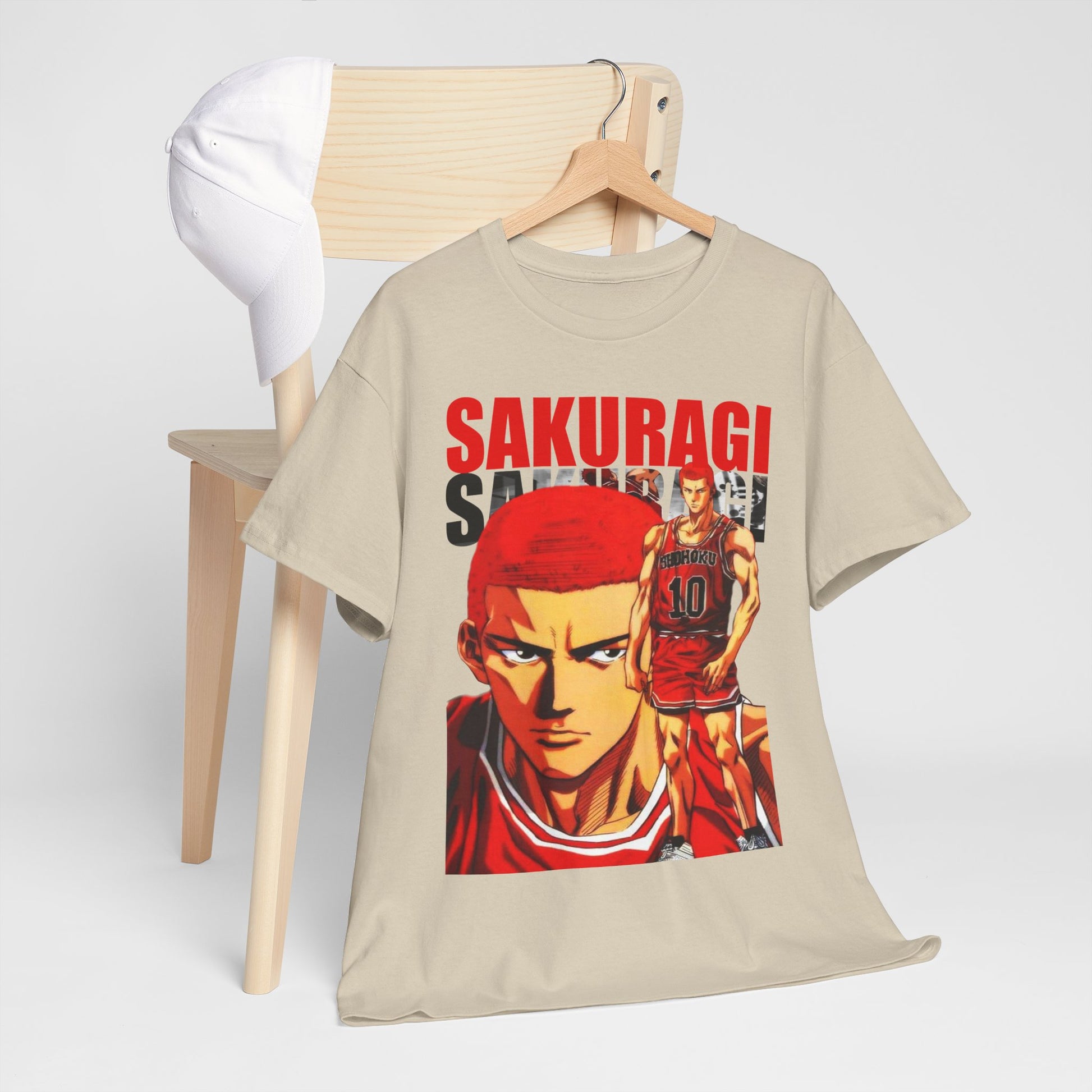 Trendsetting beige anime t-shirt featuring bold illustrations of the character Sakuragi from Slam Dunk, elegantly displayed on a wooden chair paired with a white cap.