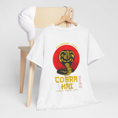 Artfully arranged white Cobra Kai t-shirt displayed alongside a white cap on a minimalist chair, exuding a calm aesthetic. An ideal combination for a contemporary, relaxed look for martial arts aficionados.