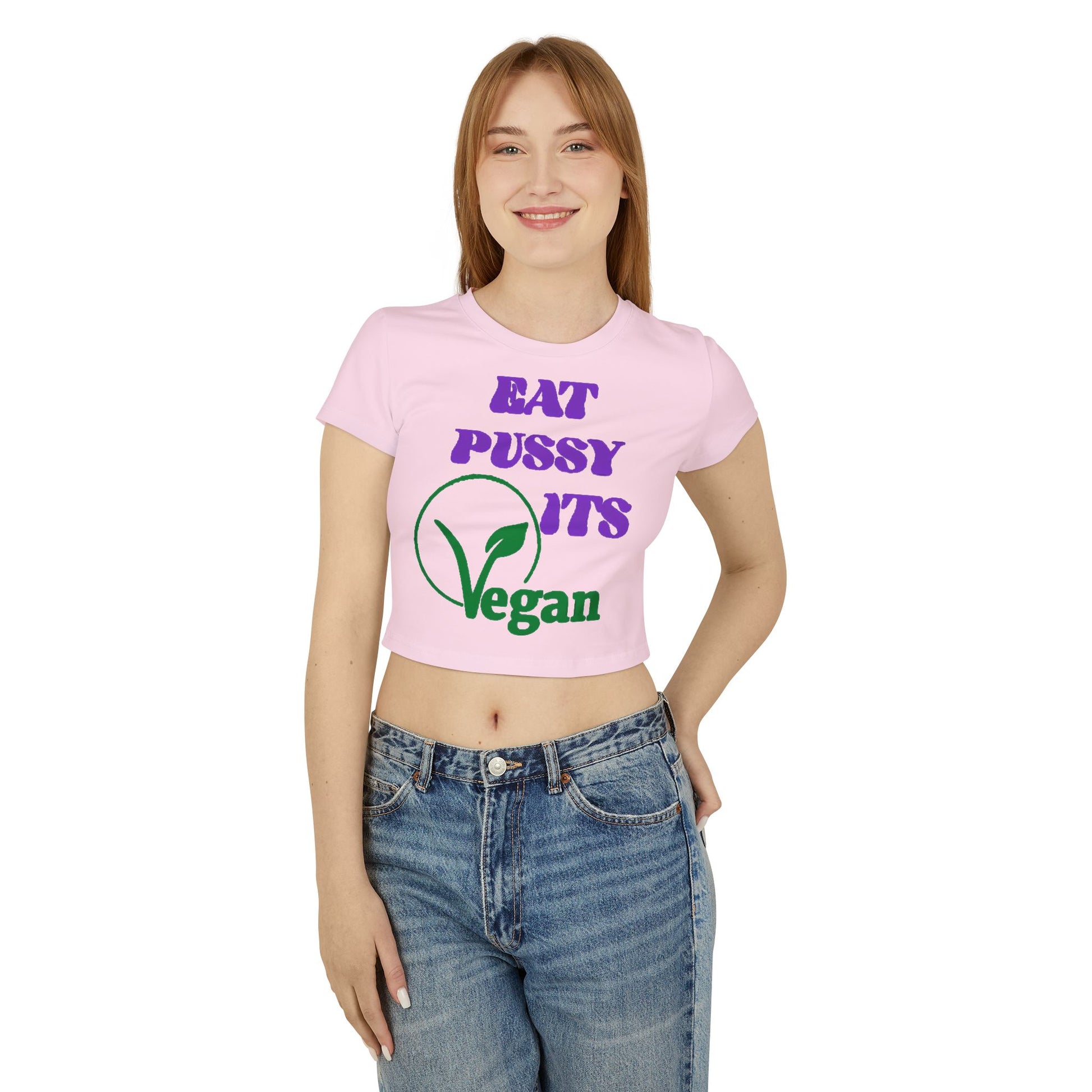 Luxurious women's cropped T-shirt featuring a humorous vegan design. The shirt is styled in a soft pink tone with bold typography displaying the phrases 'EAT PUSSY ITS Vegan' in vibrant purple and green. Perfect for the playful and eco-conscious fashion enthusiast.