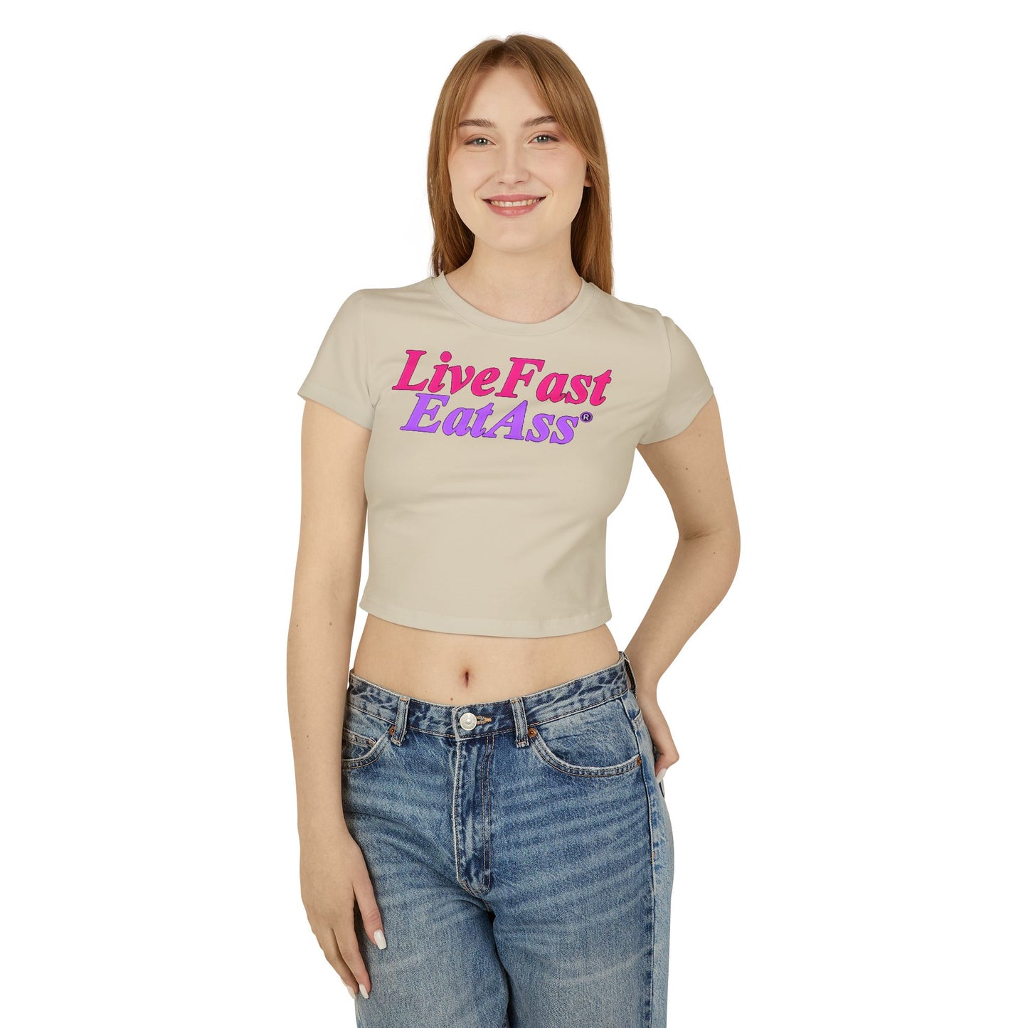Chic woman wearing a cropped t-shirt featuring the vibrant slogan 'Live Fast Eat Ass' in hot pink and purple, exuding playful luxury.
