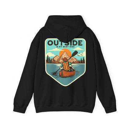 Sophisticated black hoodie showcasing a vintage-style print of a kayaker adventurously paddling on a tranquil lake, framed by breathtaking mountains at sunrise, with the phrase 'OUTSIDE IS MY BEST SIDE' elegantly highlighted.