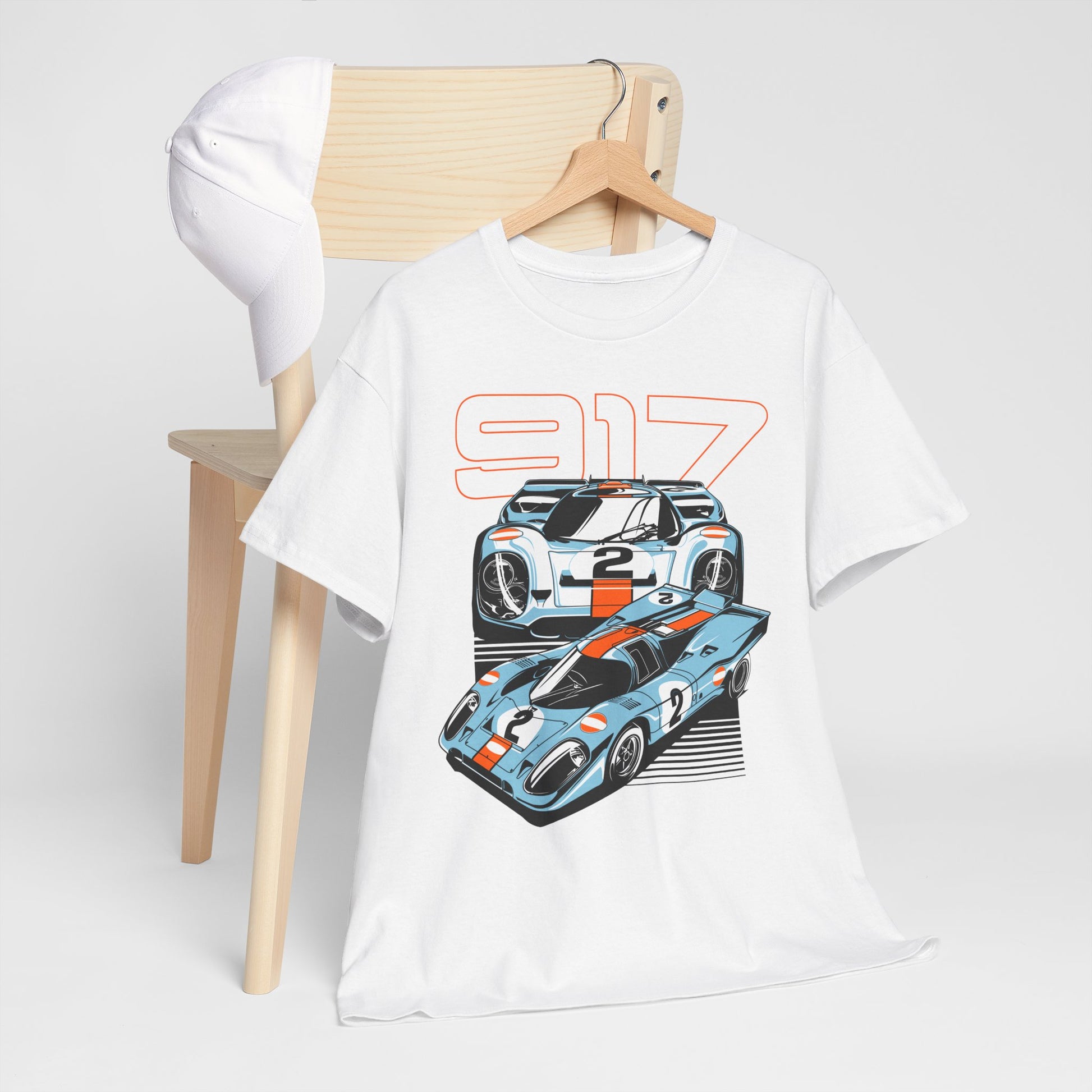 Stylish Porsche 917 graphic t-shirt displayed on a wooden chair, featuring iconic race car illustrations in vibrant blue and orange. Perfect for car enthusiasts seeking luxury and flair.