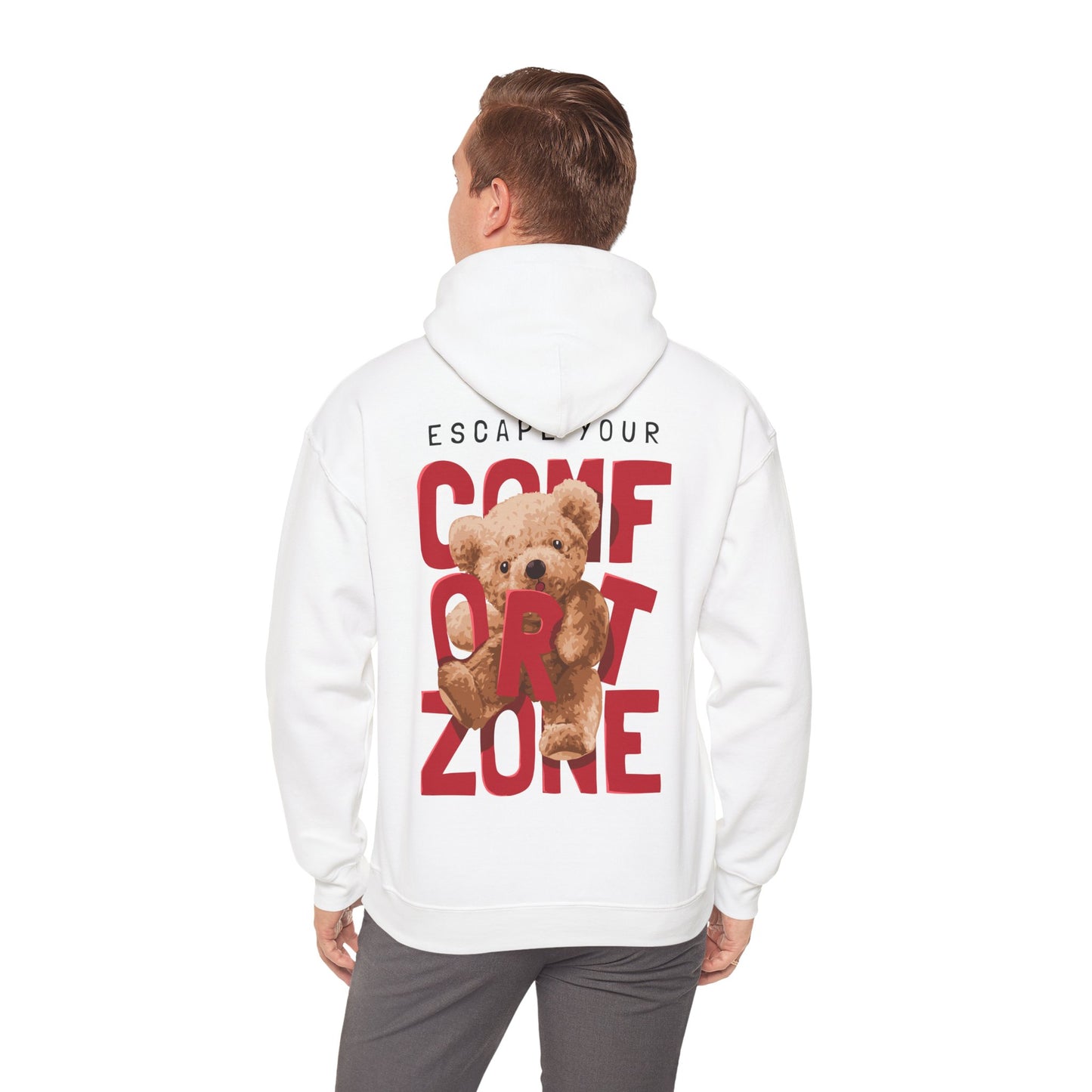 Man wearing a white hoodie with a striking teddy bear graphic and motivational text 'ESCAPE YOUR COMFORT ZONE' on the back, embodying playful luxury.