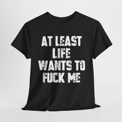 Stylishly presented black unisex cotton t-shirt showcasing the cheeky slogan 'AT LEAST LIFE WANTS TO FUCK ME', ideal for those who appreciate humour in luxury apparel.