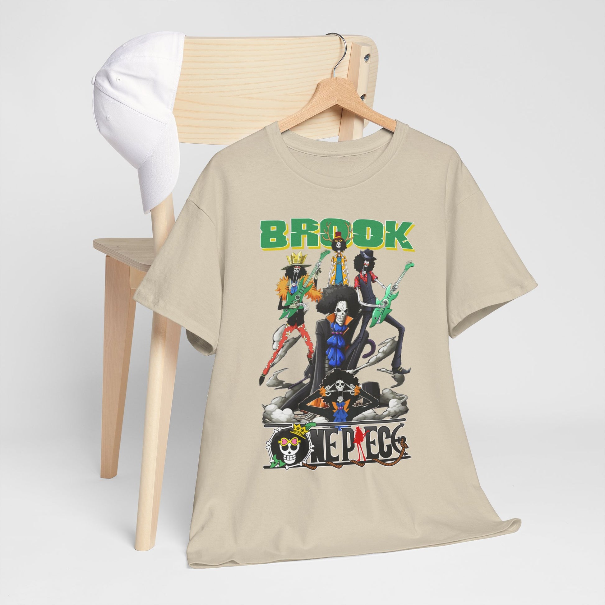 Luxurious Brook & Crew Men's T-Shirt featuring bold anime-inspired graphics, elegantly displayed on a hanger with a stylish white cap, set against a simple wooden chair backdrop.