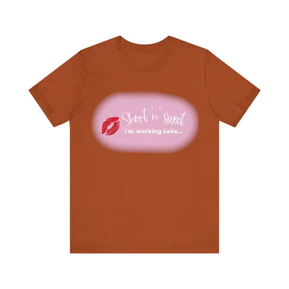 Sabrina Carpenter Inspired Unisex Short Sleeve Tee adorned with a vibrant lipstick print on a rich brown background, a luxurious choice for fashion-forward individuals.