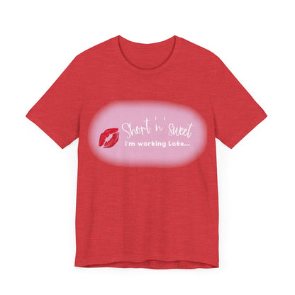 Front view of the Sabrina Carpenter Inspired Unisex Short Sleeve Tee showing a chic design with 'Short 'n' sweet, I'm working late...' text and a striking lipstick motif.