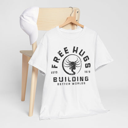 Sophisticated presentation of a white t-shirt with 'FREE HUGS' and 'BUILDING BETTER WORLDS' graphics, artfully arranged with a cap on a wooden chair for a trendy look.