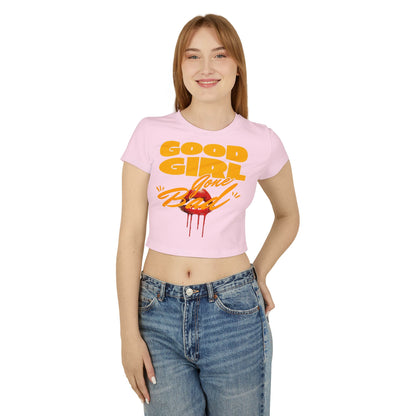 Elegant woman showcasing the Cheeky Women's Crop Tee titled 'Good Girl Gone Bad' in a soft pink hue, featuring bold orange-yellow lettering and a striking lip graphic, perfect for playful and confident fashion statements.