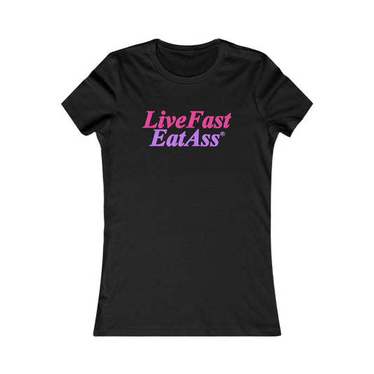 Luxurious black fitted women's t-shirt showcasing the striking phrase 'Live Fast, Eat Ass®' in a stylish pink and purple gradient, ideal for trendy, bold fashion.