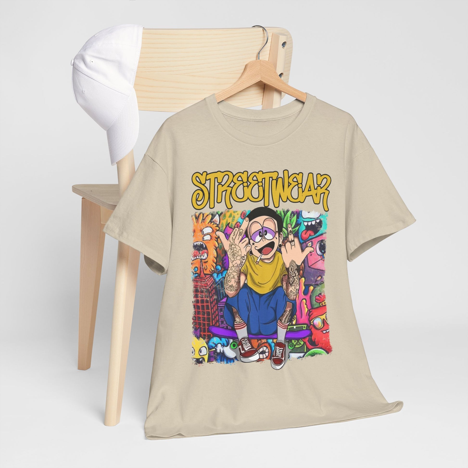 Chic beige streetwear t-shirt showcased on a wooden chair with a white cap, highlighting its eye-catching cartoon design and bold urban graphics.