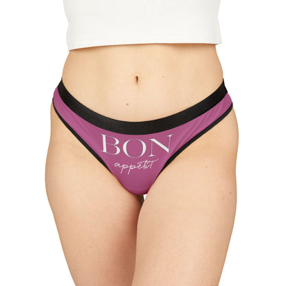 Elegant women's thong in pink with black trim featuring the playful slogan 'BON appétit', designed for a cheeky and luxurious touch to intimate wear.