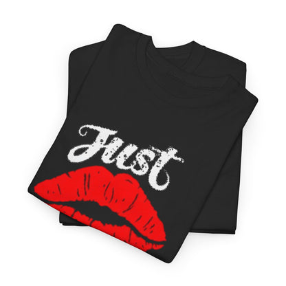 Elegant stack of unisex black cotton t-shirts displaying a striking graphic of red lips and the playful text 'Just Kiss Me!', ideal for modern wardrobe essentials.