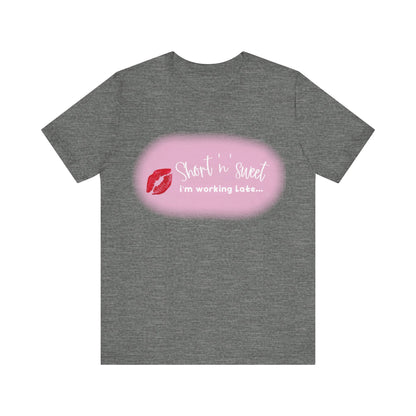 Sabrina Carpenter Inspired Unisex Short Sleeve Tee with Vibrant Lipstick Print in dark grey, displaying the playful text 'Short n' sweet i'm working Late...' alongside a vibrant red lipstick imprint.