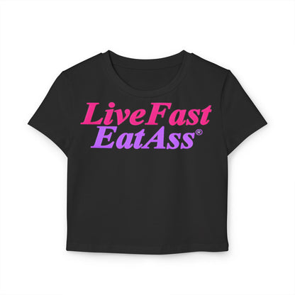 Luxurious cropped t-shirt in black featuring a vibrant graphic design that reads 'Live Fast EatAss®' in pink and purple, perfect for making a bold fashion statement.