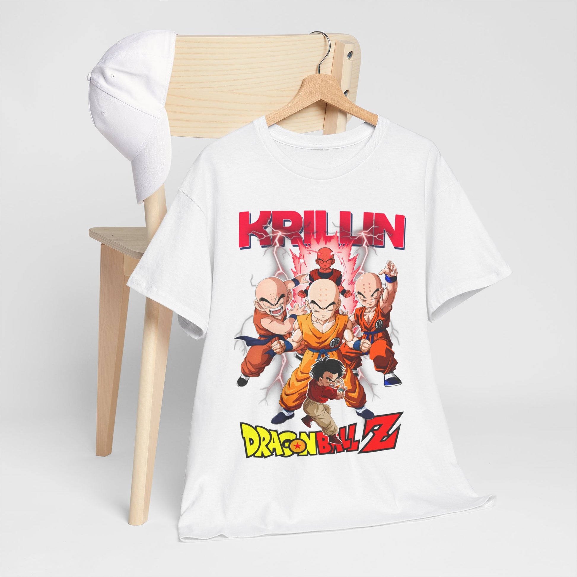 Luxurious white Dragon Ball Z T-shirt featuring Krillin and iconic characters, elegantly displayed on a wooden chair alongside a stylish cap.