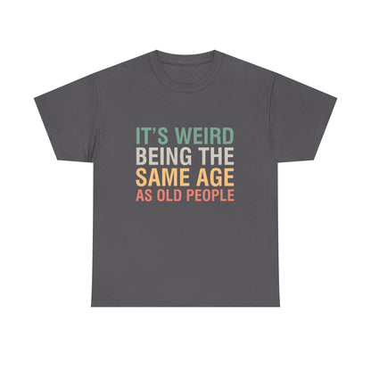 A luxurious urban unisex cotton T-shirt featuring the playful message 'It’s Weird Being The Same Age As Old People' in vibrant colours against a chic grey backdrop, perfect for casual outings.